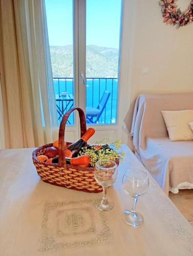 a basket of vegetables on a table with two wine glasses at Odysseion Apartments in Vathi, Ithaka