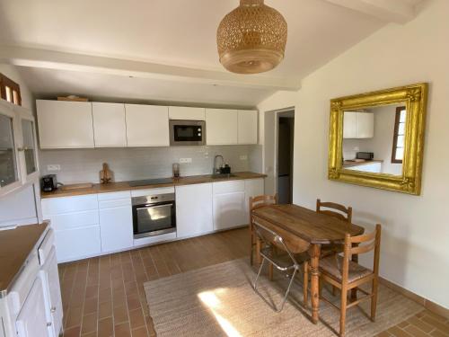 - une cuisine avec des placards blancs, une table et un miroir dans l'établissement Collinette des Lecques, à Saint-Cyr-sur-Mer