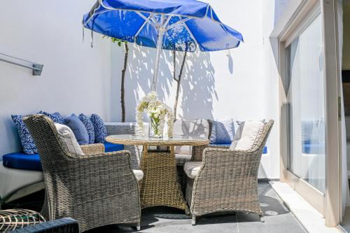 a table with chairs and a blue umbrella at Georgia Pelekanou Studios in Fira