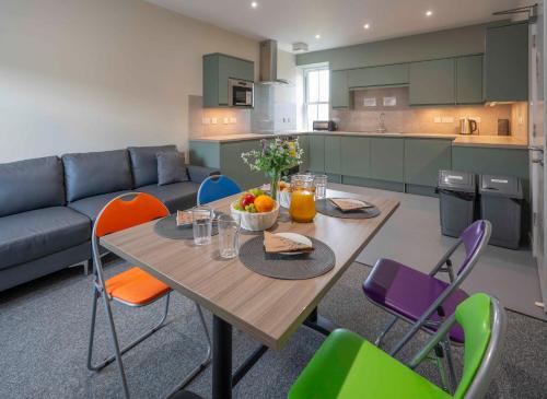 eine Küche mit einem Holztisch mit Stühlen und einem Sofa in der Unterkunft Newcastleton Bunkhouse in Newcastleton