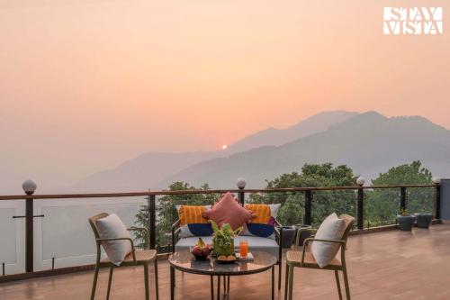 a balcony with a table and chairs with a view of mountains at StayVista at Barkat Villa with Jacuzzi in Rāmgarh