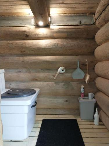 a bathroom with a toilet in a wooden wall at Kuukkelin Koto in Hämeenlinna