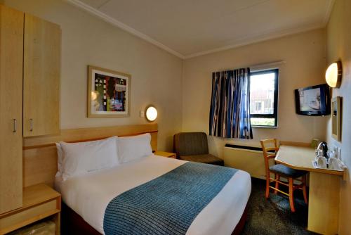 um quarto de hotel com uma cama grande e uma secretária em Road Lodge Centurion em Centurion