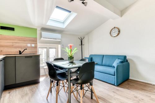 un salon avec une table et un canapé bleu dans l'établissement Côté Palais 2-Climatisé-Netflix-Fibre, à Carcassonne