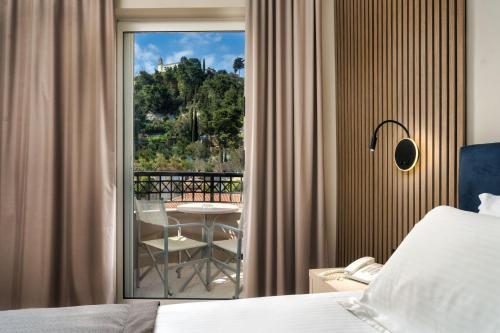 a bedroom with a bed and a balcony with a table at Palatino Hotel in Zakynthos