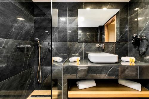 ein Bad mit einer Dusche, einem Waschbecken und einem Spiegel in der Unterkunft Palatino Hotel in Zakynthos