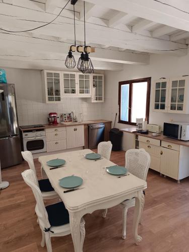 une cuisine avec une table blanche et des chaises dans l'établissement Maison cœur de village, à Collias