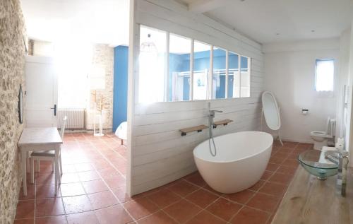 une salle de bain avec une baignoire blanche et des toilettes dans l'établissement Maison de charme avec suite parentale et grande piscine extérieure, à Anglade