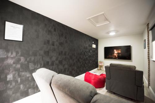 a living room with a couch and a tv on a wall at Palm Cottage in Reading