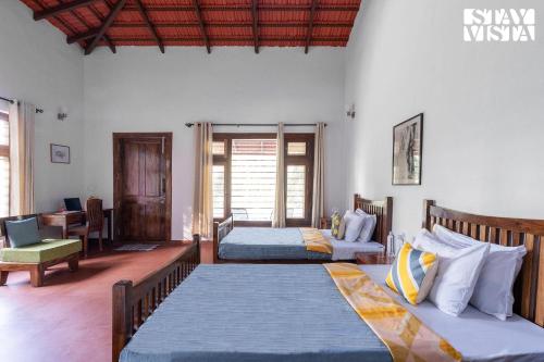 a bedroom with two beds and a desk at StayVista at Villa Estuaire with Bathtub in Madikeri