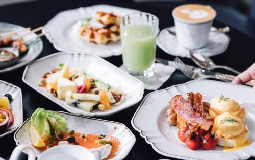 una mesa con platos de comida y una taza de café en Rosewood Bangkok en Bangkok