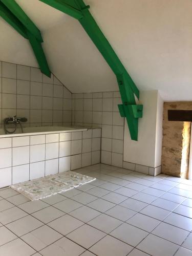 um quarto no sótão com pisos em azulejo branco e vigas verdes em "Castel" em Saint-Amand-de-Coly