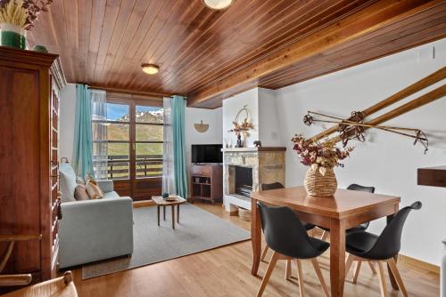a living room with a wooden ceiling and a table and chairs at Garbo by Cardi Suites in Formigal