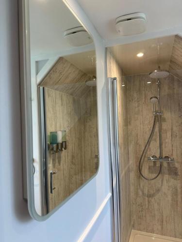 a bathroom with a shower with a mirror at Stratheyre Cottage in Portree
