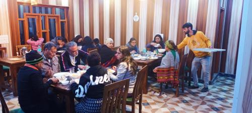 a group of people sitting at tables in a restaurant at D’SHIEKHS RESORT GUREZ in Kanzalwan