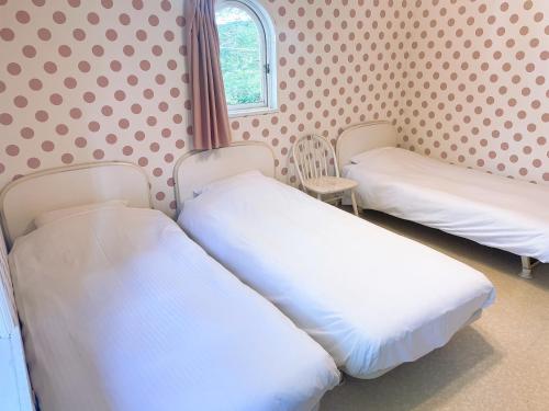 two beds in a room with polka dot wallpaper at Karuizawa Pension Sato no Nukumori in Karuizawa
