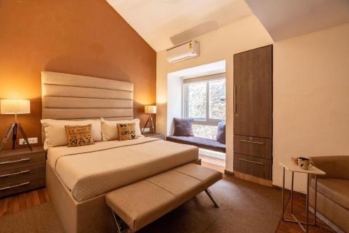 um quarto com uma cama grande e uma janela em StayVista at Oberoi's Chalet em Bhimtal