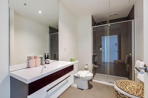 a bathroom with a white sink and a toilet at Skyline Allure - Urban Wellness meets City Living in Melbourne