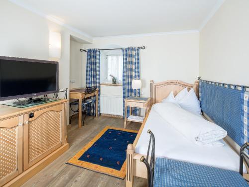 a living room with a bed and a flat screen tv at Gasthof Schopper in Breitenbach am Inn