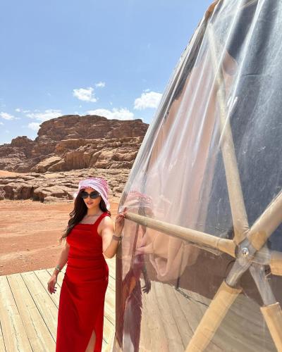 a woman in a red dress standing next to a veil at Wadi Rum Calma camp in Aqaba