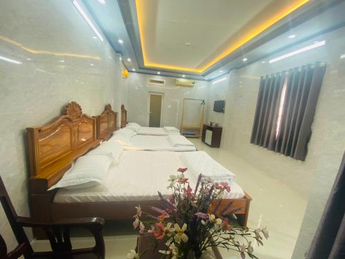 芹苴的住宿－PHÚ PHƯƠNG NAM HOTEL，一间卧室配有一张大床和一张鲜花桌