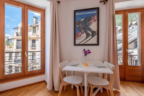 une table blanche et des chaises dans une pièce avec une fenêtre dans l'établissement Studio Hors Piste, à Chamonix-Mont-Blanc