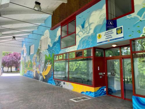 un edificio con un mural en el costado en Albergue de Villava, en Villava