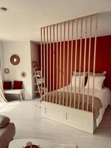 un berceau blanc dans une pièce avec un mur rouge dans l'établissement Studio cosy, à Étaples
