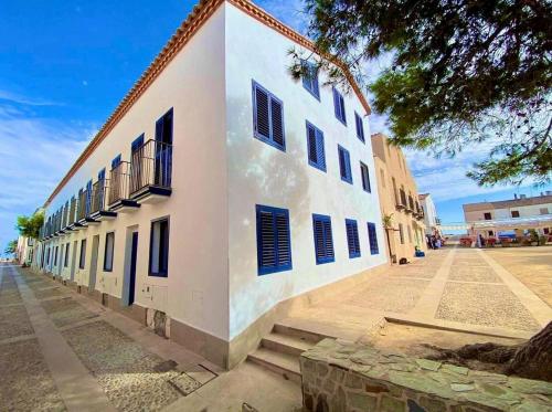 a white building with blue shutters on a street at La Esquineta de Vientos de Tabarca in Tabarca