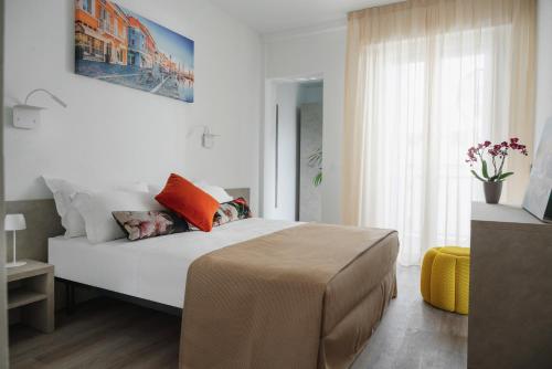 a bedroom with a large white bed with orange pillows at Nido Suite & Apartments in Cesenatico