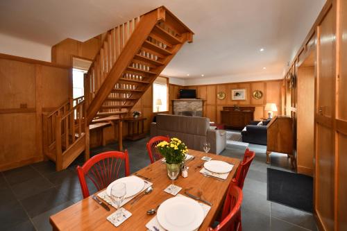 a dining room with a wooden table with red chairs at Cloncaird Castle Estate Cottages in Maybole