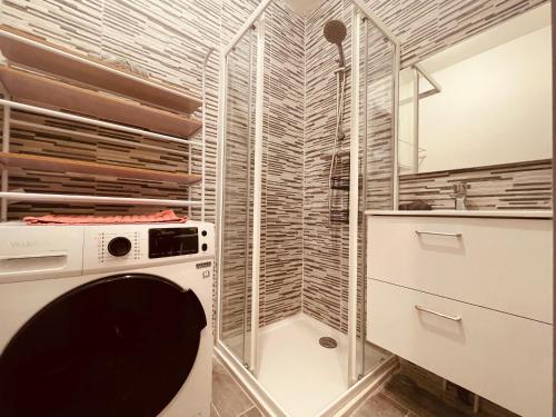 une buanderie avec un lave-linge et une paroi en verre dans l'établissement Tropicana - 297, à Rouen