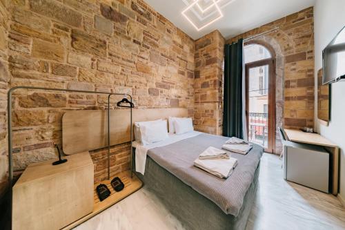 a room with a bed and a brick wall at Chios City Inn in Chios