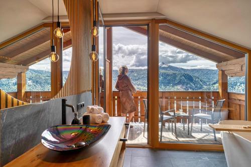 a woman standing in a bathroom with a large window at Chalet Schlossberg Schwarzhorn in Nova Ponente