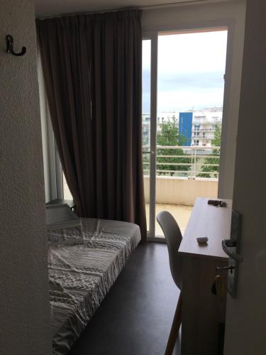 une chambre avec un lit, un bureau et une fenêtre dans l'établissement APPARTEMENT IDEAL FAMILLE, à La Rochelle