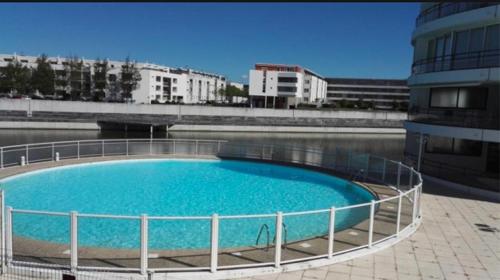 une grande piscine d'eau bleue à côté d'un bâtiment dans l'établissement APPARTEMENT IDEAL FAMILLE, à La Rochelle