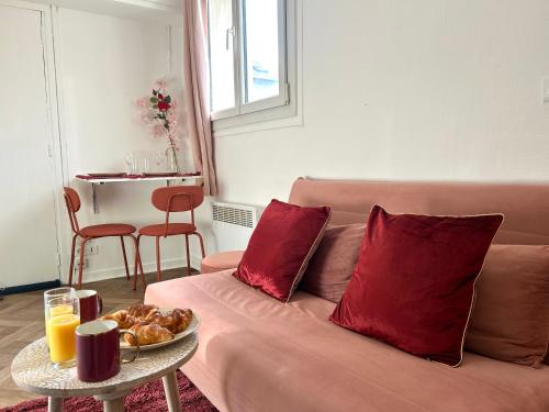 ein Wohnzimmer mit einem Sofa mit roten Kissen und einem Tisch in der Unterkunft Aurore - Château de Versailles - Central in Versailles