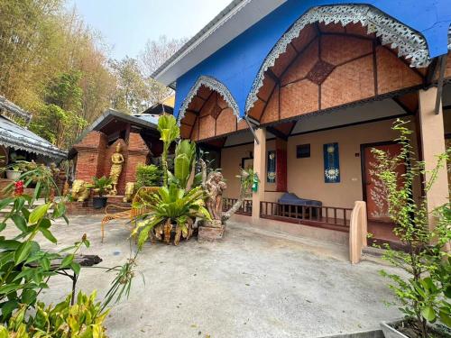 a house with a blue facade with a courtyard at Phu Jaya Floresta Resort by ALPHATEL PARTNER in Chiang Mai