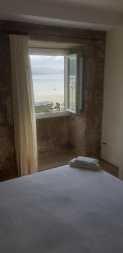 Un dormitorio con una cama y una ventana con vista al mar. en La Casa de Ana en Fisterra, en Finisterre