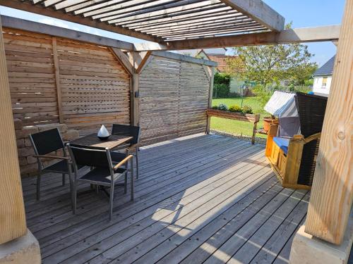 eine Holzterrasse mit einem Tisch und Stühlen unter einer Pergola in der Unterkunft Störmthal Ferienwohnung 2 Sonnenweg in Großpösna