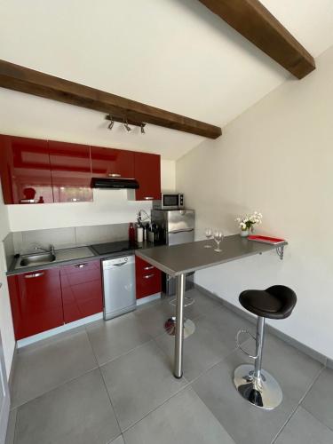 une cuisine avec des placards rouges et une table avec un tabouret dans l'établissement Studio charmant avec terrasse, à Lançon-Provence