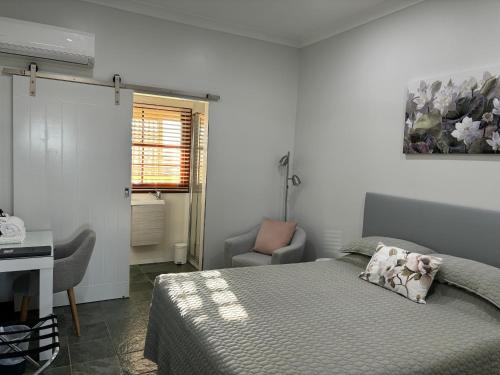 1 dormitorio con cama, escritorio y silla en The Block Vista B&B en Nanango