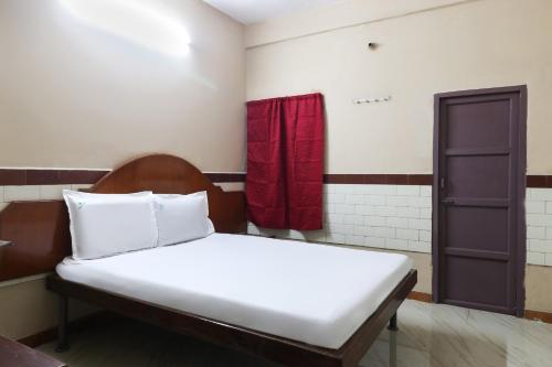 a bed in a room with a red curtain at OYO Jayanthi Mansion in Chennai