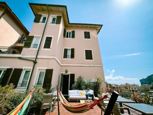 un uomo seduto su un'amaca davanti a un edificio di Hotel Bello by Ostello Bello a Finale Ligure