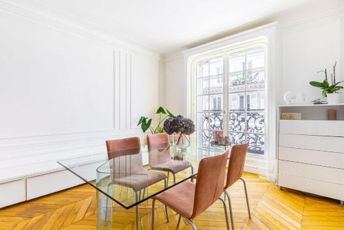 une salle à manger avec une table et des chaises en verre dans l'établissement GuestReady - Grand apt lumineux à Montmartre, à Paris