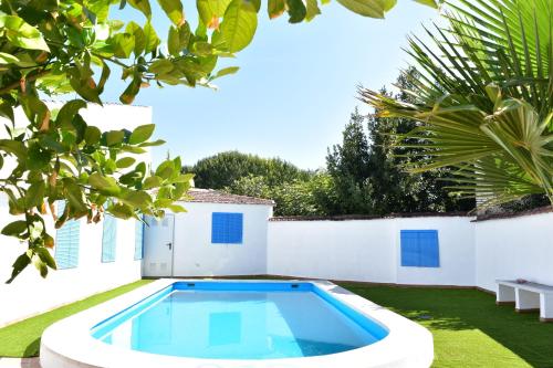a swimming pool in the yard of a house with a white wall at Casa Rural Huerta Sartén in Pinos Puente