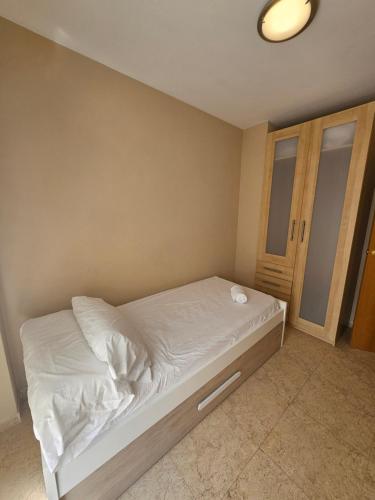 a small bedroom with a bed with white sheets at Chalet adosado en la playa in Cullera