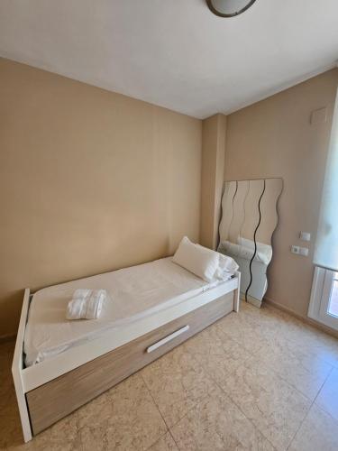 a small bedroom with a bed with white sheets at Chalet adosado en la playa in Cullera