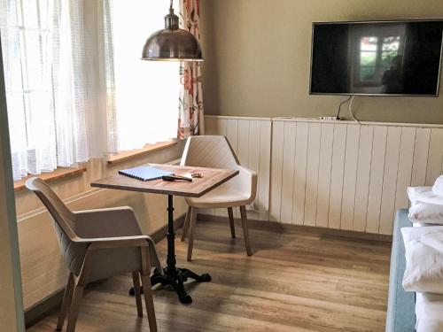 グリンデルワルトにあるApartment Chalet Auf dem Vogelstein-2 by Interhomeのテーブル、椅子、テレビが備わる客室です。