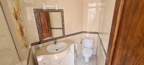 een badkamer met een wastafel, een toilet en een spiegel bij Casa San José in Nerja
